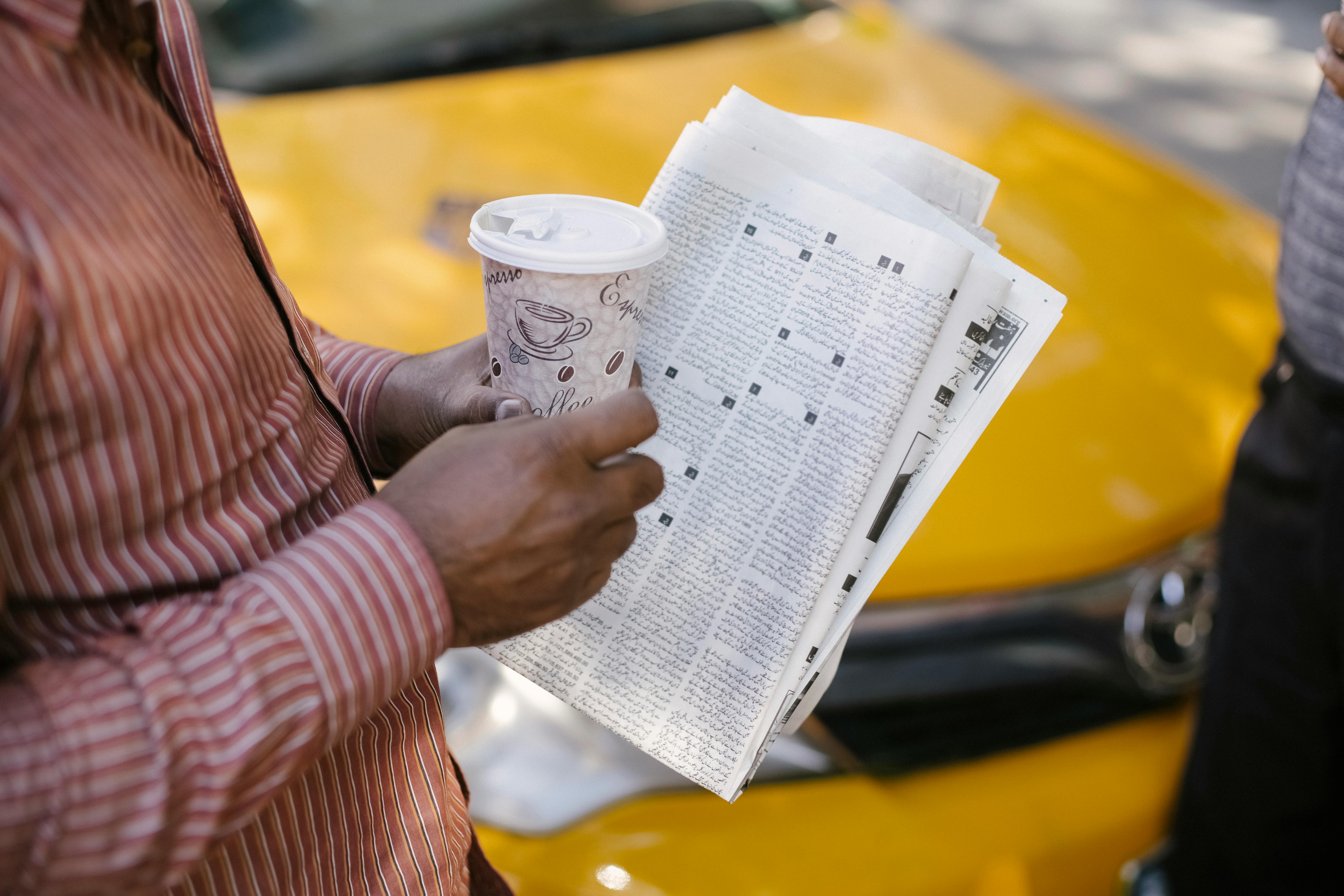 crop ethnic taxi driver with takeaway coffee interacting with colleague