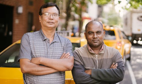 Confident diverse taxi drivers with crossed arms on urban road