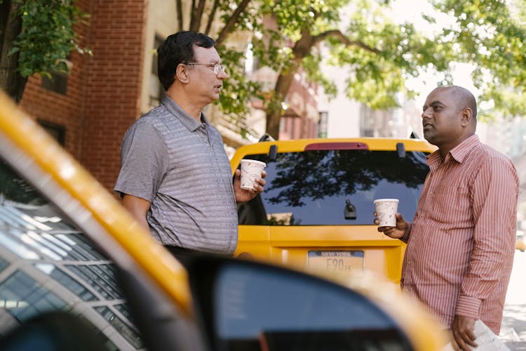 Multiracial Taxi Drivers With Takeaway Coffee Talking On City Street