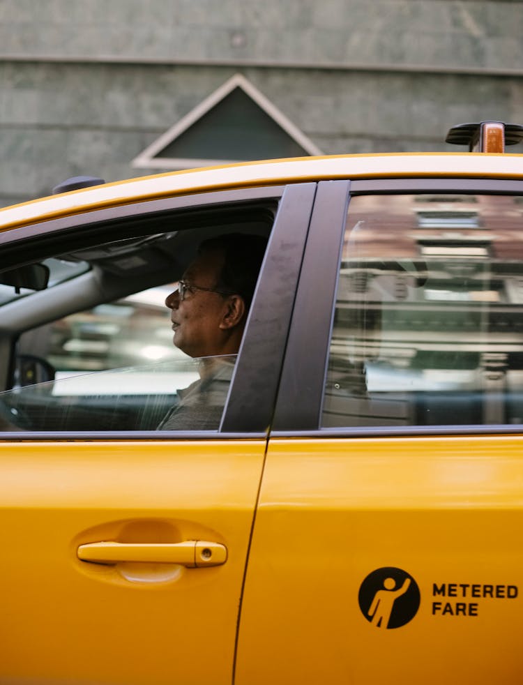 Attentive Asian Male Taxi Driver In Modern Car