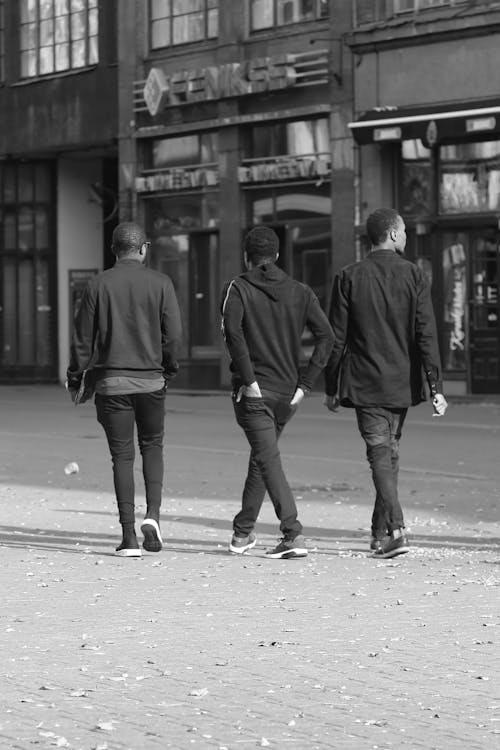 Grayscale Photo of Three Men Walking in the Street
