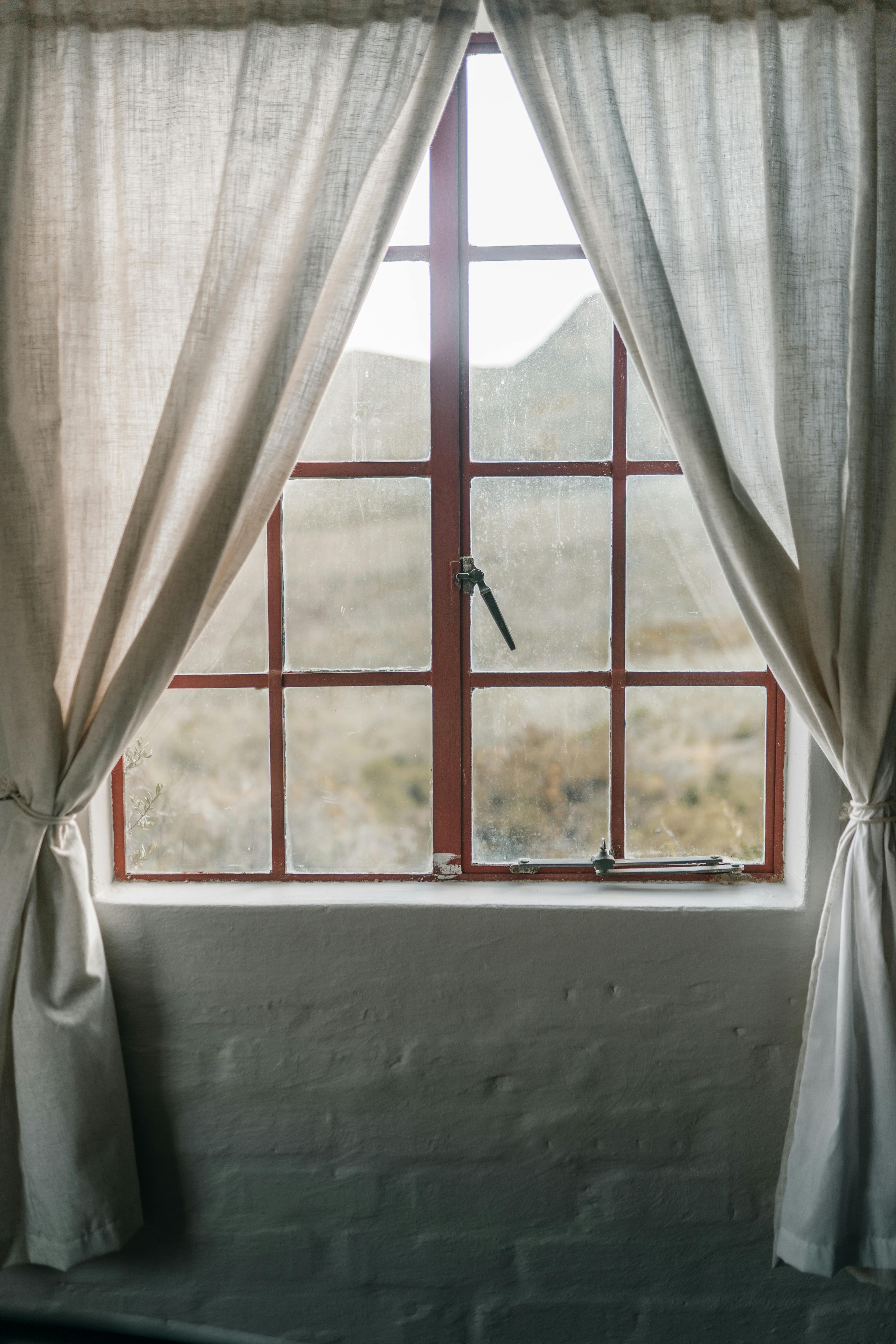 red framed glass window with white curtains