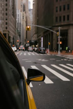 Modern taxi near crosswalk on street of city with buildings and traffic lights