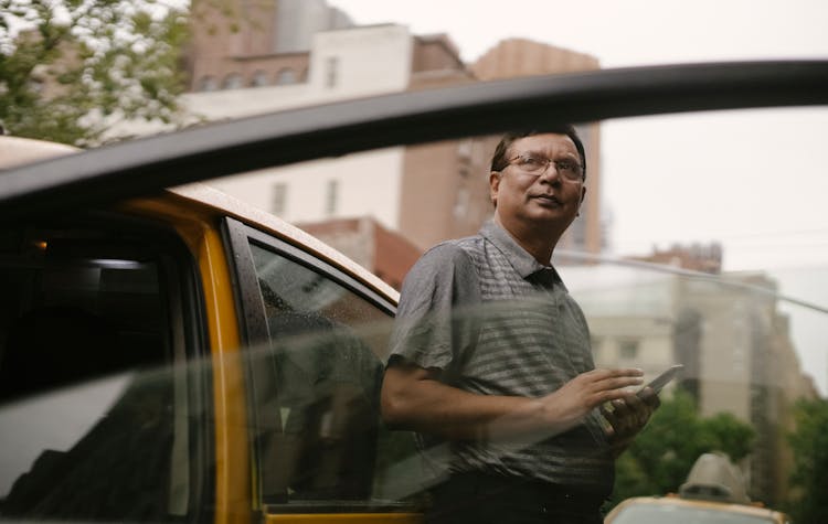 Ethnic Man Leaning On Taxi With Smartphone