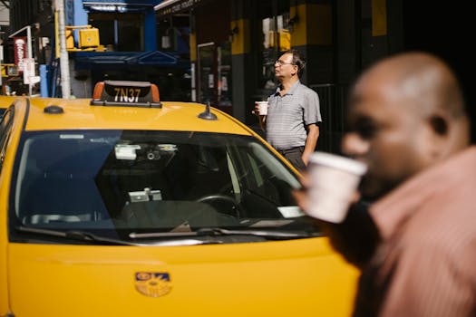 Unrecognizable men standing near taxi and drinking hot beverage from paper cups on city street
