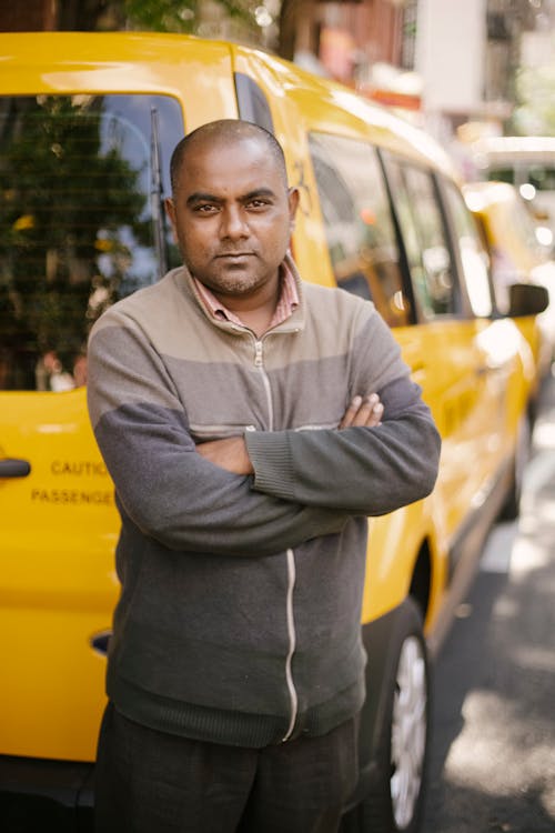 Ethnic man standing near taxi on street