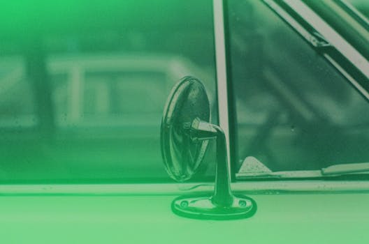 A detailed shot of a classic car's side mirror with a green filter effect.