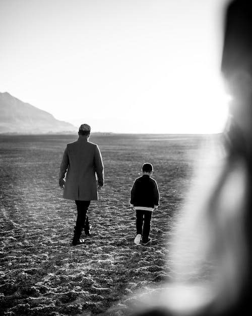 Free Black and White Photo of a Person Walking with a Child  Stock Photo