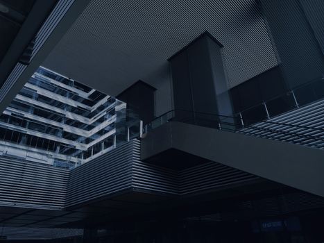 From below of modern building with glass and concrete walls and stairs with metal railings on dark day