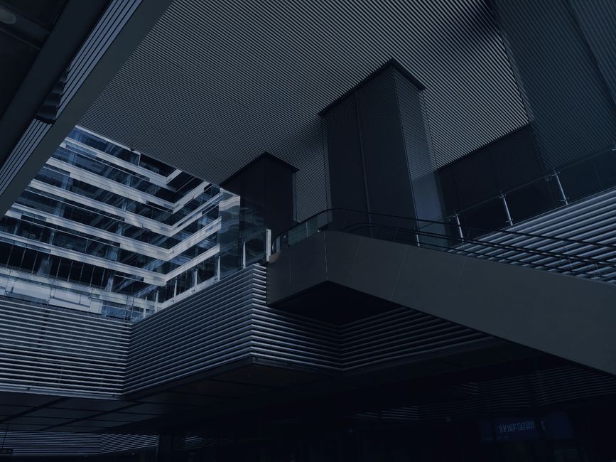 From below of modern building with glass and concrete walls and stairs with metal railings on dark day