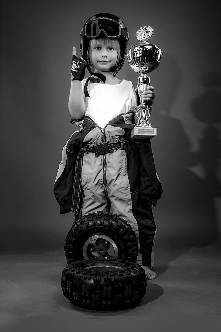 Grayscale Photo Of A Child Holding A Trophy