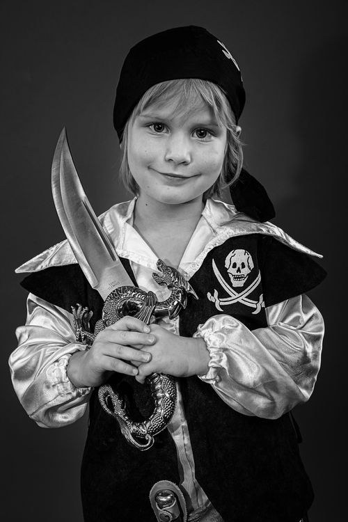 Free Black and white portrait of a young child in a pirate costume, displaying a playful and confident pose. Stock Photo