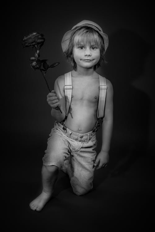 Grayscale Photo of Boy Holding Flower