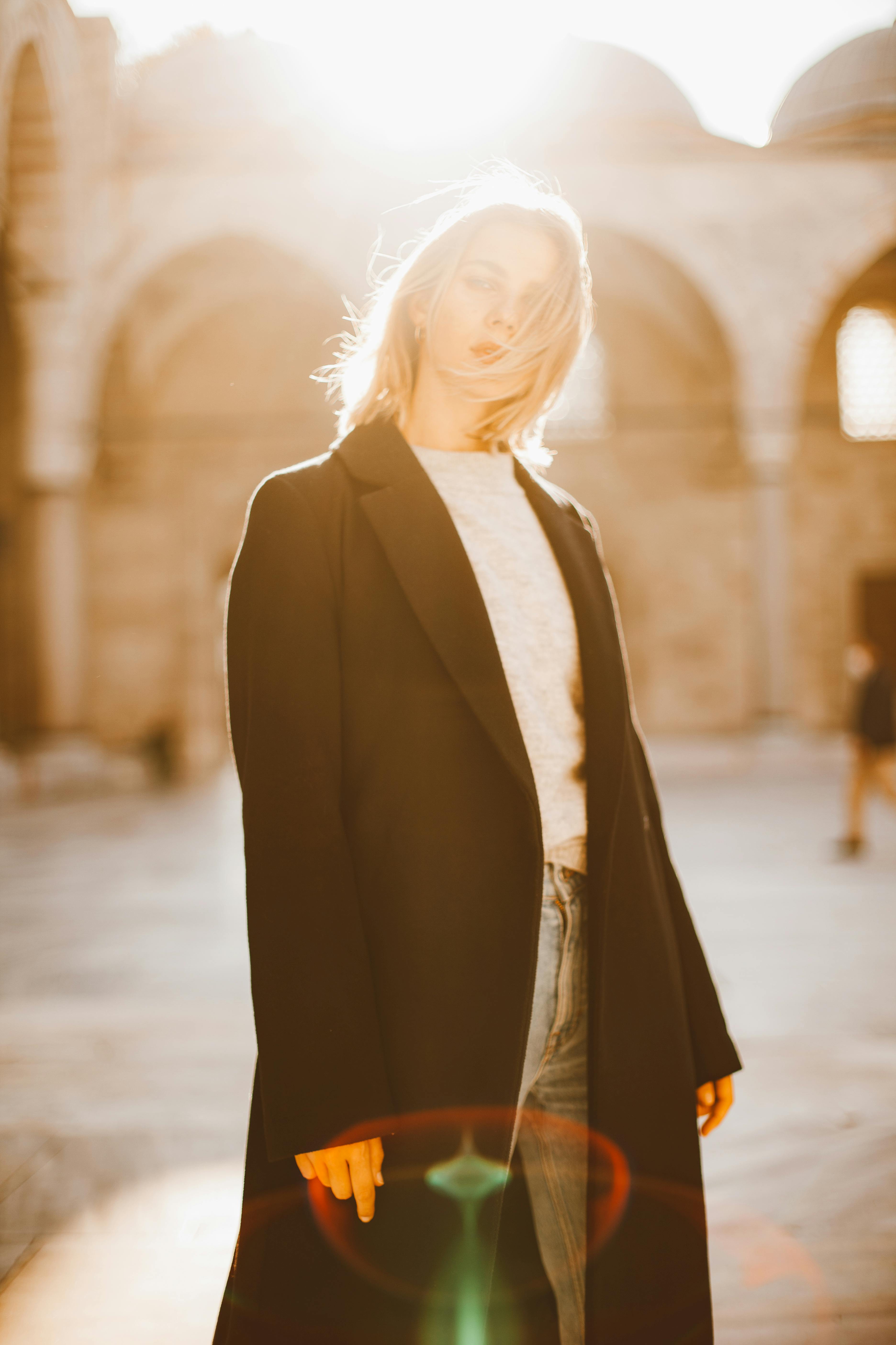 woman in black coat standing against the light