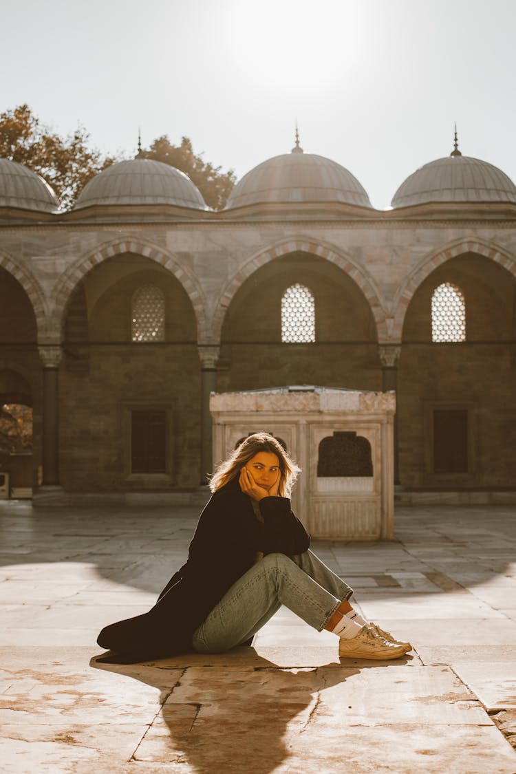 Woman In Black Coat Sitting On Tiled Floor 