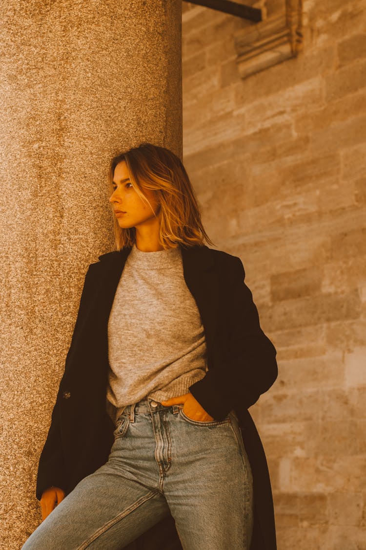 Woman In Gray T Shirt And Black Trench Coat Posing On A Post