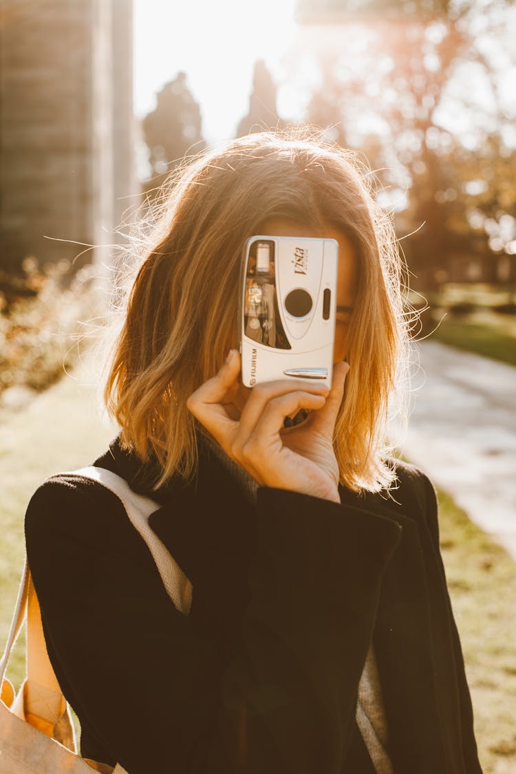 Woman Holding Silver Camera Against Face