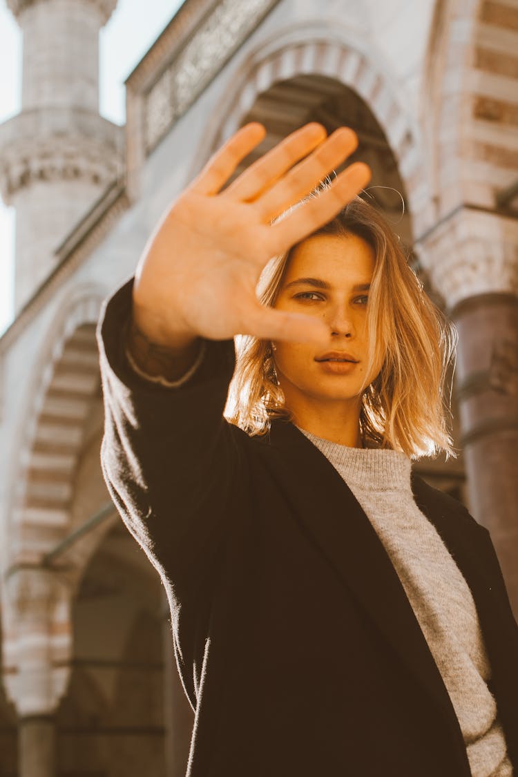 Woman In Black Long Sleeve Shirt With Hand Raised Against Face