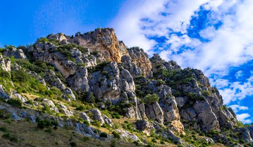 Free Vivid rocky cliff landscape with lush greenery under a bright blue sky. Stock Photo