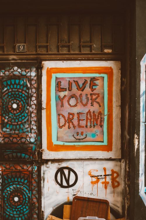 Free A colorful graffiti art with the message 'Live Your Dream' painted on an urban wall. Stock Photo