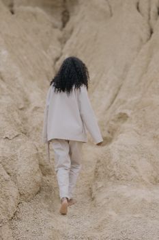 一个卷发女人赤脚走在沙地上，象征着孤独