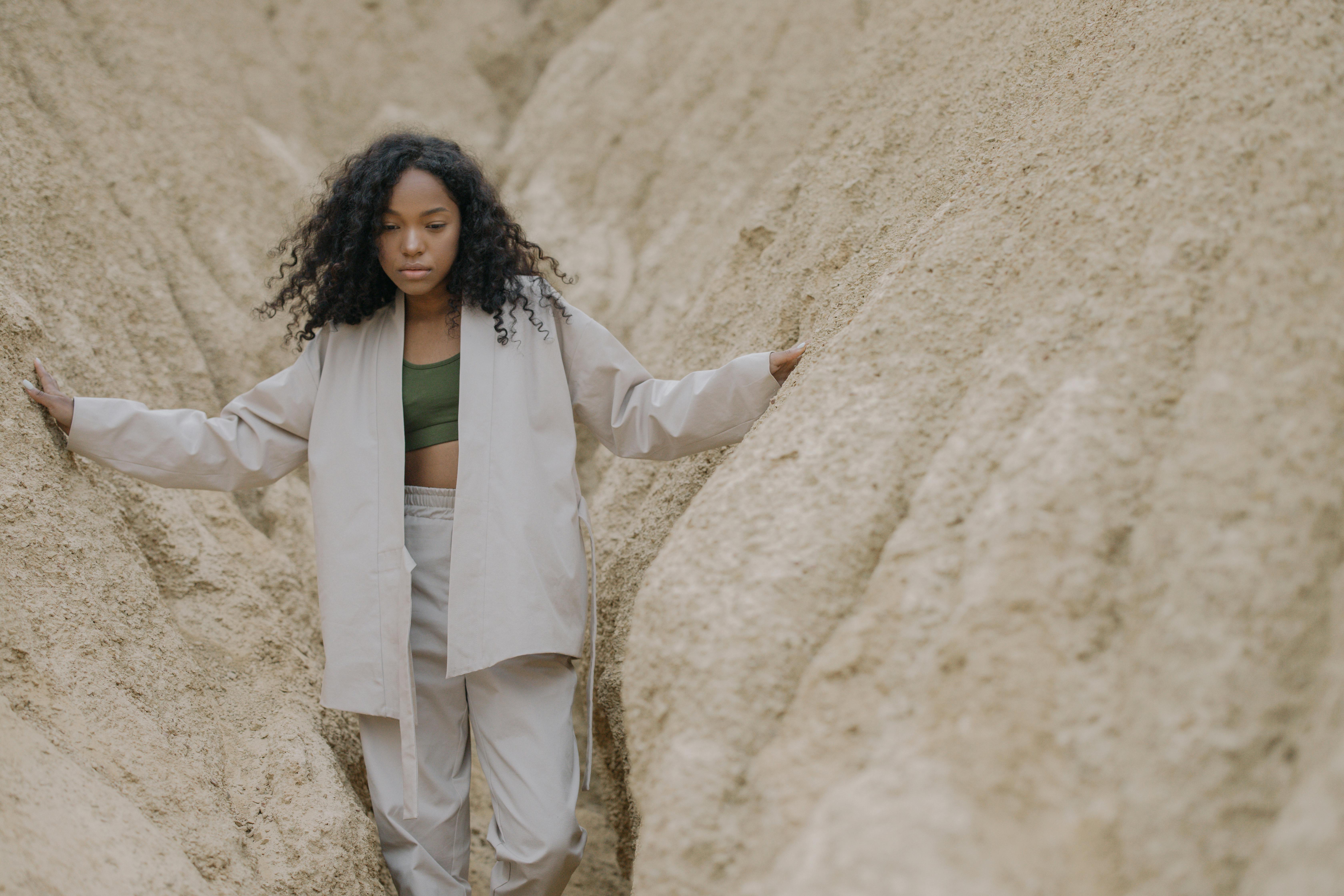 woman in white pajama standing between brown rough walls