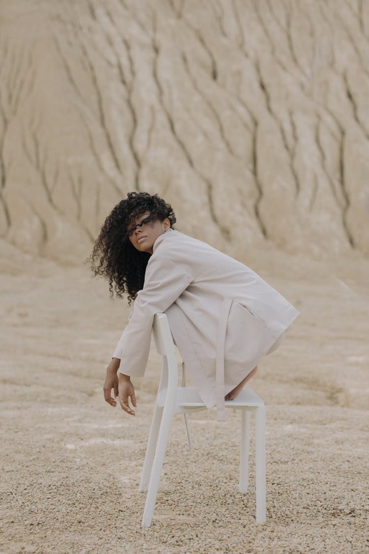 Woman In White Jacket Sitting On Top Of White Chair