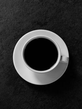 黑色纹理表面上的白瓷杯里黑咖啡的俯视图