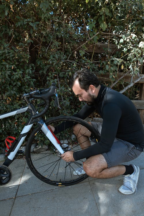 Man in Black Long Sleeve Shirt Fixing His Bike