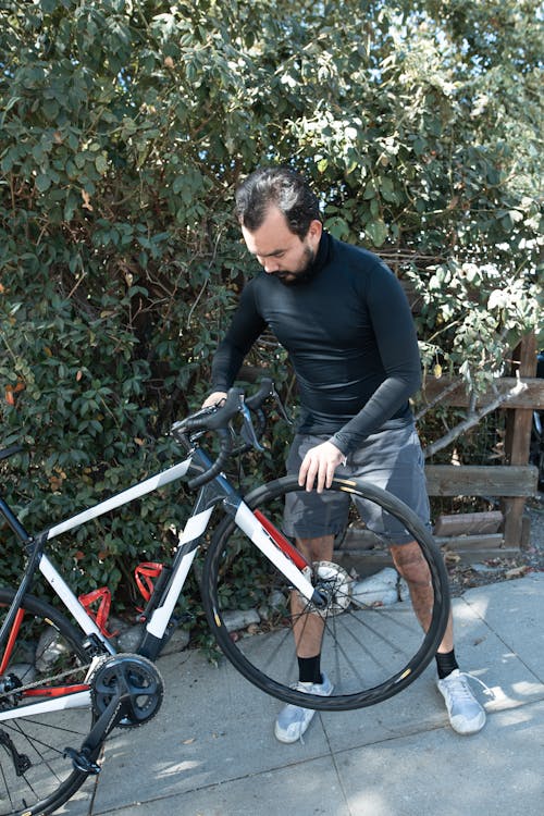 Uomo In Camicia Nera A Maniche Lunghe In Sella A Una Bicicletta Rossa