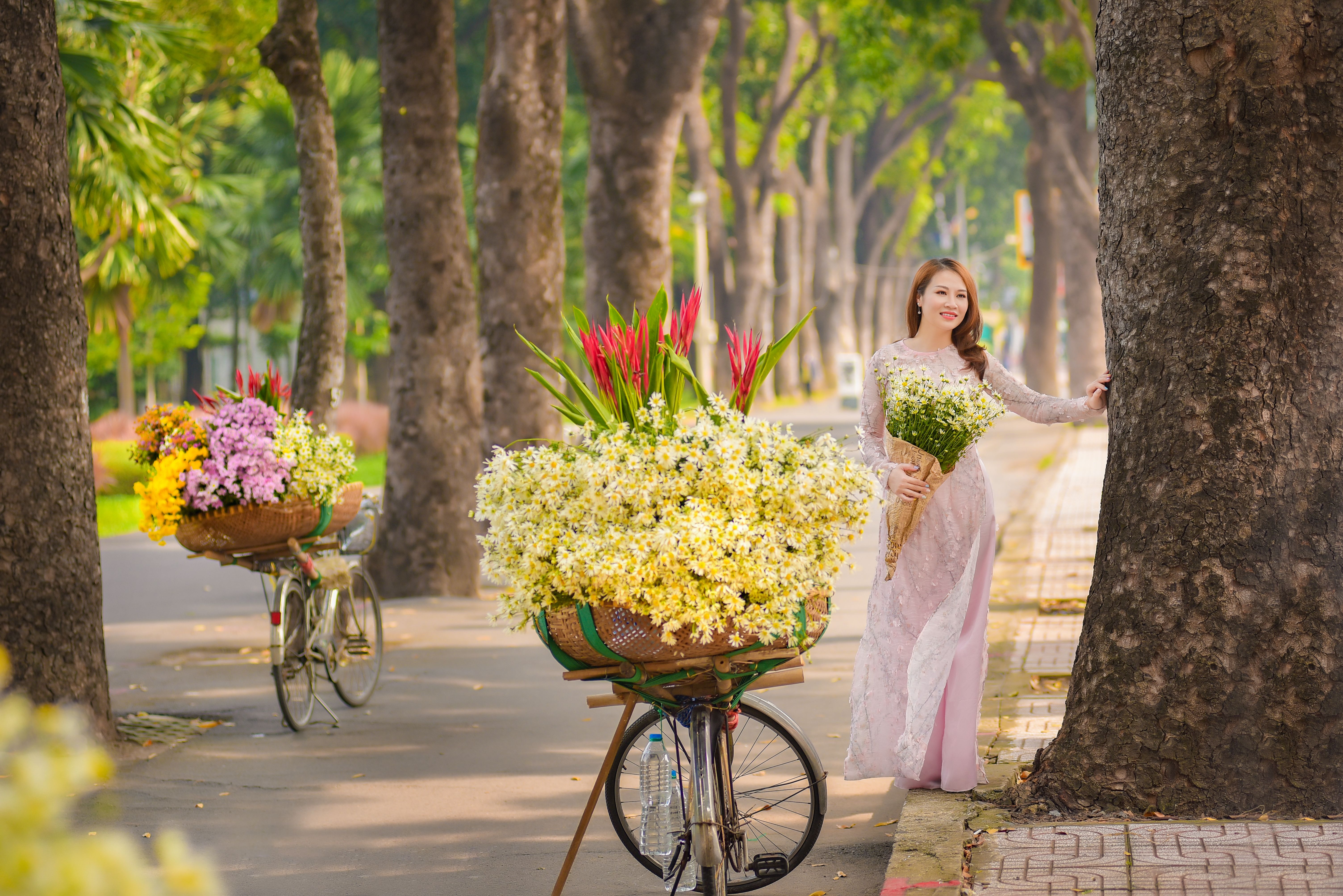 Woman in Traditional Dress Standing Beside a Tree Trunk · Free Stock Photo