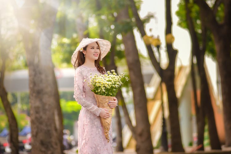 Woman In Tradition Dress And Hat Holding A Bunch Of Flowers