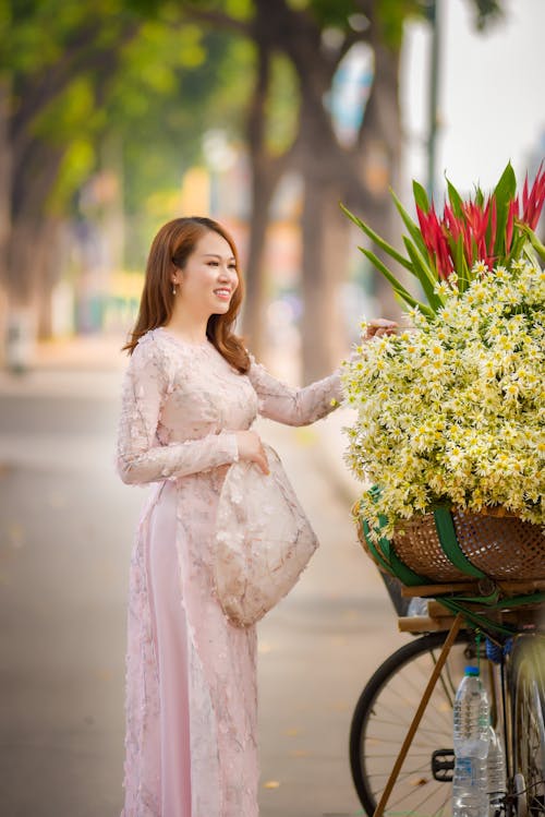 Woman in Traditional Dress Looking at Flowers