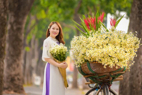 Woman in White Traditional Dress Holding a Bouquet