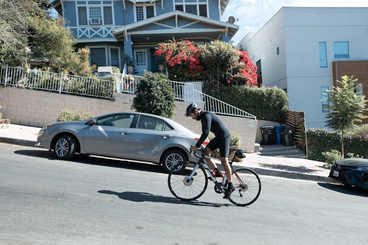 A Man Riding A Bicycle In An Uphill Road