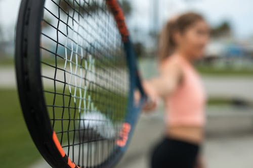 Wanita Dengan Tank Top Pink Dan Celana Pendek Hitam Memegang Raket Tenis Merah Dan Hitam