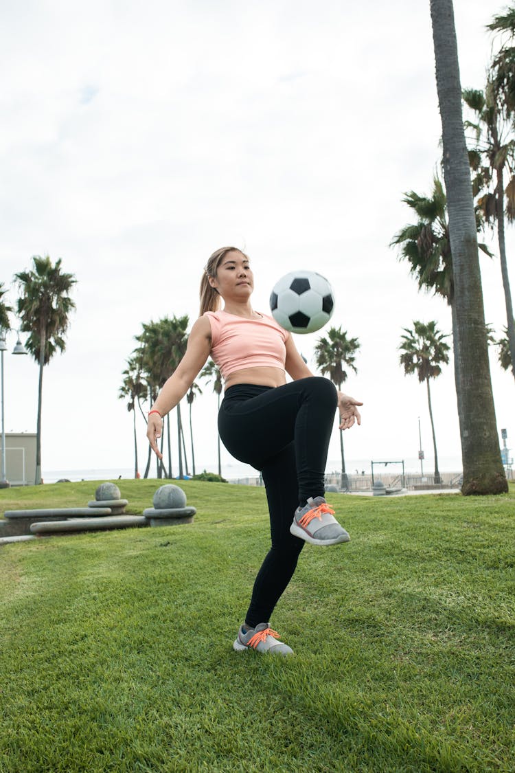 A Woman Juggling A Soccer Ball With Her Knee
