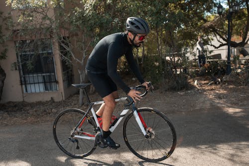 무료 빨간색과 흰색 도로 자전거를 타는 검은 색 긴 소매 셔츠를 입은 남자 스톡 사진