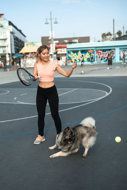 Free A Woman Playing Tennis with a Dog Stock Photo