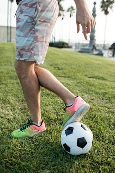 Close-up of a soccer player's legs and ball on a sunny field.