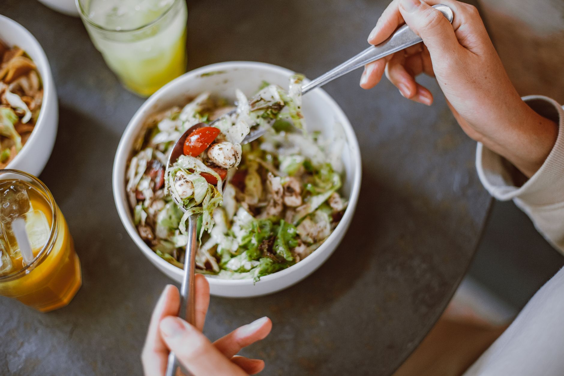 外食族健康飲食平衡術:實用策略讓你吃得安心 A person enjoying a fresh salad with cherry tomatoes and greens indoors.