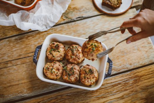 Close-up of homemade meatballs with herbs in a dish on a wooden table. Perfect for food photography.