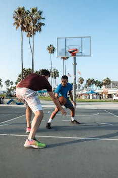 Two men playing basketball on an outdoor court at Venice Beach.