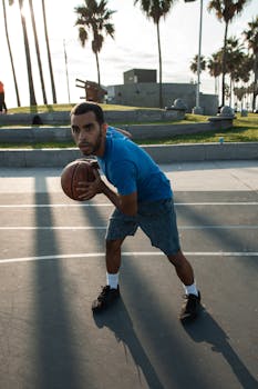 A young man intensely focusing as he plays basketball on an outdoor court.