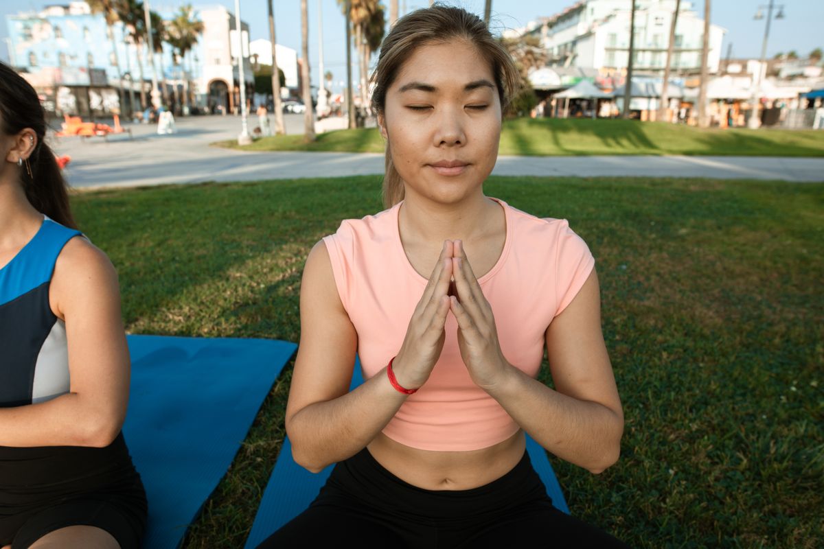 Woman sitting outdoors in a park with eyes closed, practising focused breathing