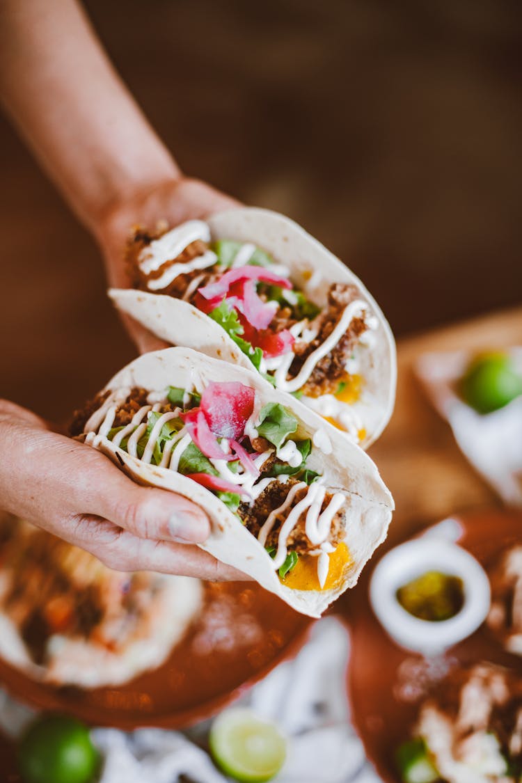 A Person Holding Tortilla Wraps With Lettuce And Beef