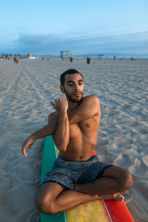 A Man Sitting on a Surfboard Stretching