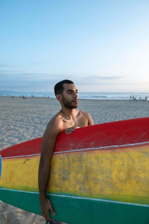 Hombre En Topless Sentado En La Tabla De Surf Roja Y Amarilla