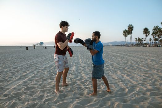 日出时分，两名男子在沙滩上练习拳击，展现了他们对健身和积极生活方式的追求