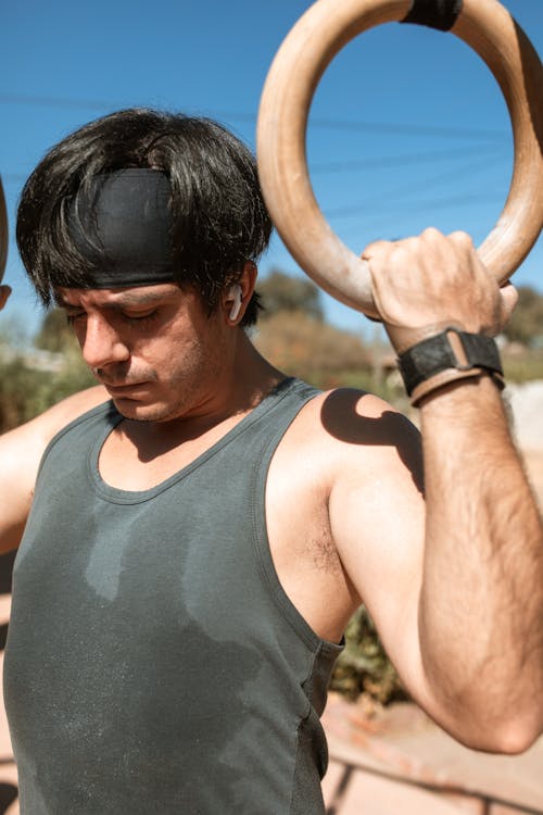 Man in Gray Tank Top Holding Brown Wooden Rings